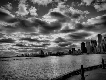 City at waterfront against dramatic sky