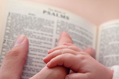 Cropped hand of baby and parent on book