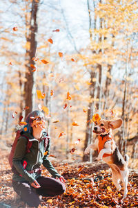 Side view of woman with dog on tree trunk