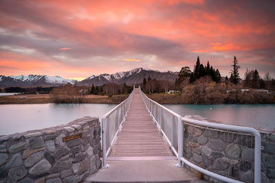 Pier over lake against sky during sunset