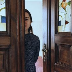 Close-up of young woman standing against door