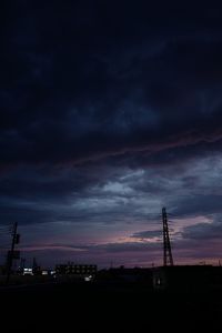 Silhouette of electricity pylon against cloudy sky