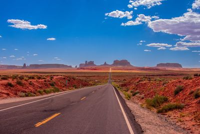 Road passing through landscape against blue sky