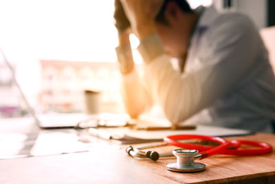Stressed doctor with stethoscope in foreground