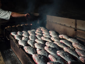 Cropped hand preparing fishes on barbecue grill