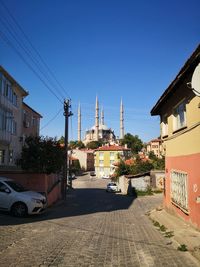 Street amidst buildings against clear blue sky