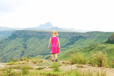 Rear view of woman standing on landscape against sky