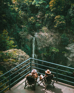 High angle view of people sitting at observation point against waterfall