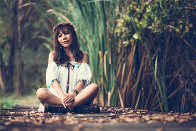 Portrait of woman sitting on boardwalk at park