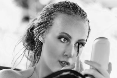 Close-up of young woman applying make-up