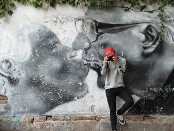 Man photographing against mural wall