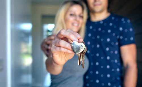 Woman holding keys while standing by man at home