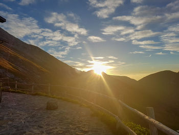 Sunlight streaming on landscape against sky during sunset