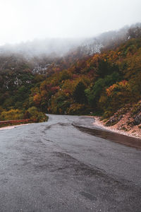 Road amidst trees against sky during autumn