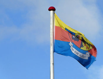 Low angle view of flag against blue sky