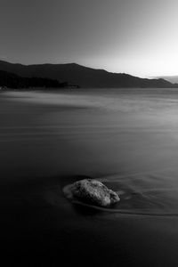 Scenic view of rocks on sea against clear sky