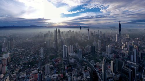 Aerial view of city against cloudy sky