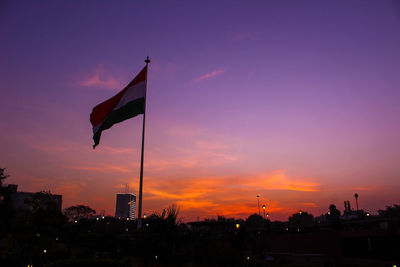 Low angle view of flag against orange sky