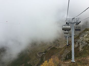 Overhead cable car over mountains against sky