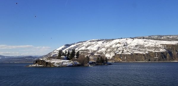 Scenic view of sea and mountains against clear blue sky