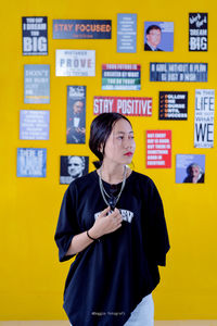 Full length of woman standing against yellow wall