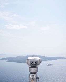 Close-up of coin-operated binoculars on sea against sky