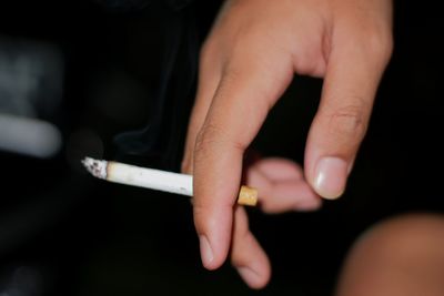 Close-up of hand holding cigarette