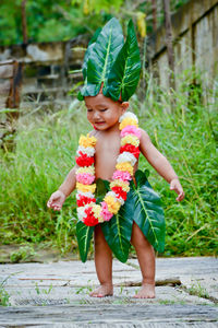 Cute boy wearing leaves and garland standing outdoors