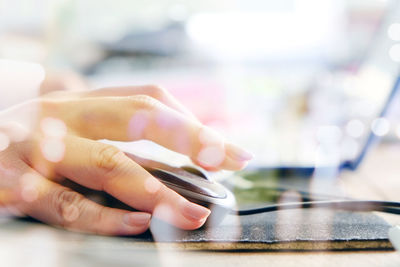 Close-up of human hand using mouse at desk