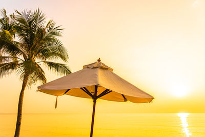 Built structure on beach against sky during sunset