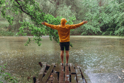 Rear view of person standing by lake