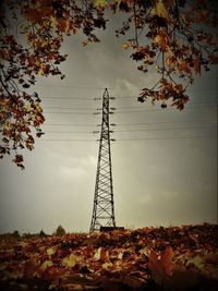 Low angle view of electricity pylon on field against sky