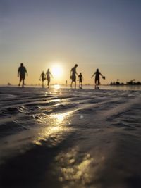 Silhouette people walking at beach during sunset