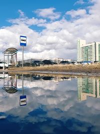 Reflection of road sign on water against sky