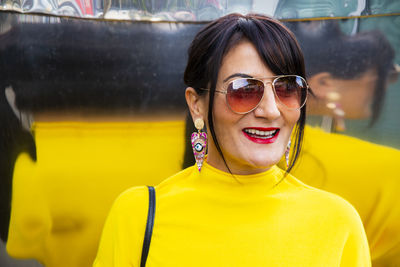 Fashionable mature woman wearing yellow top and sunglasses in city