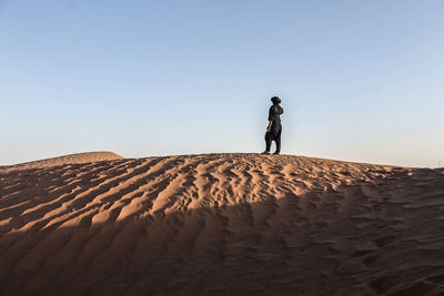 Woman standing on sand dune
