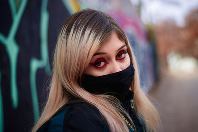 Portrait of young woman wearing mask outdoors