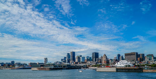 Sea by cityscape against blue sky