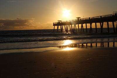 Silhouette pier on beach against sky during sunset