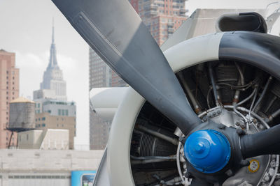Close-up of jet engine against empire state building in city
