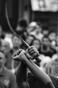 Cropped hands holding sword during event in city