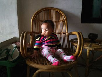 Cute girl sitting on chair at home