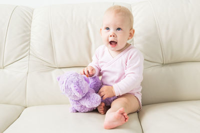 Portrait of cute baby girl on sofa at home