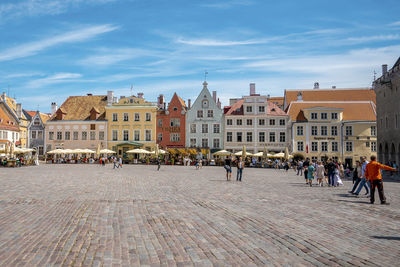 Male and female tourists exploring city square in historic town against sky