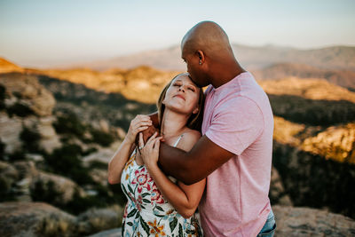 Loving couple hugging and kissing on top of mountain