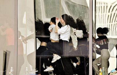 Rear view of women standing in mirror