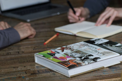 Midsection of person reading book on table