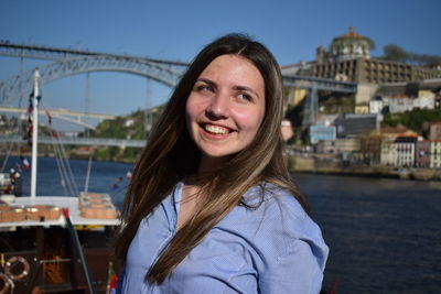 Portrait of smiling young woman against water