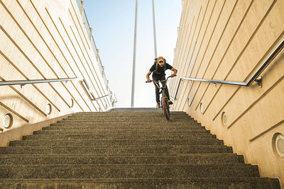 Low angle view of young man riding bicycle on steps