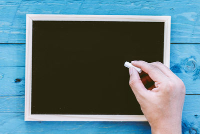 Cropped hand writing on blackboard 